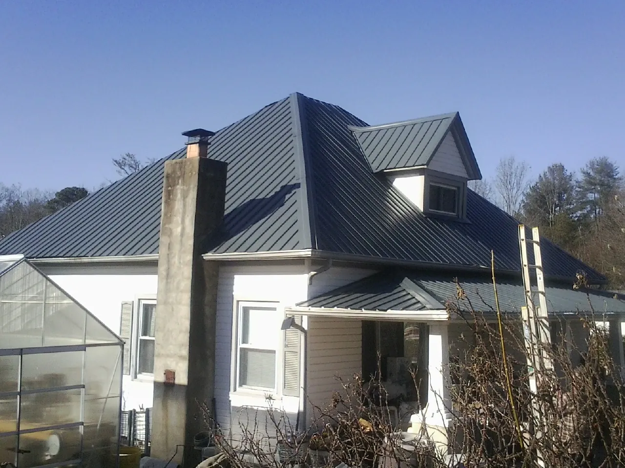 Dark blue standing seam metal roof on a white farmhouse with dormer — Slate & Tile Roof Repair by Roofing Brothers in Jobstown