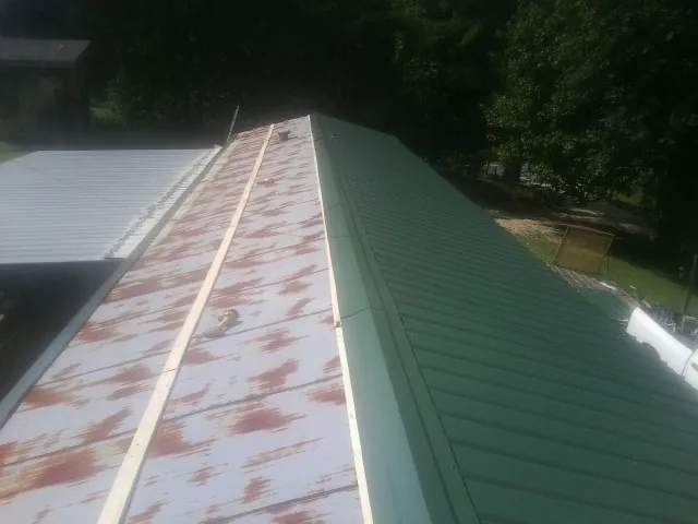 Old rusted panels beside newly installed green metal roofing — Wind Damage Roof Repair by Roofing Brothers in Jobstown