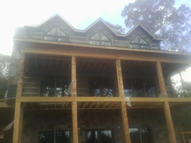 Dormers and porch framing on a large log home under construction — Roof Coating work by our crew in Jobstown