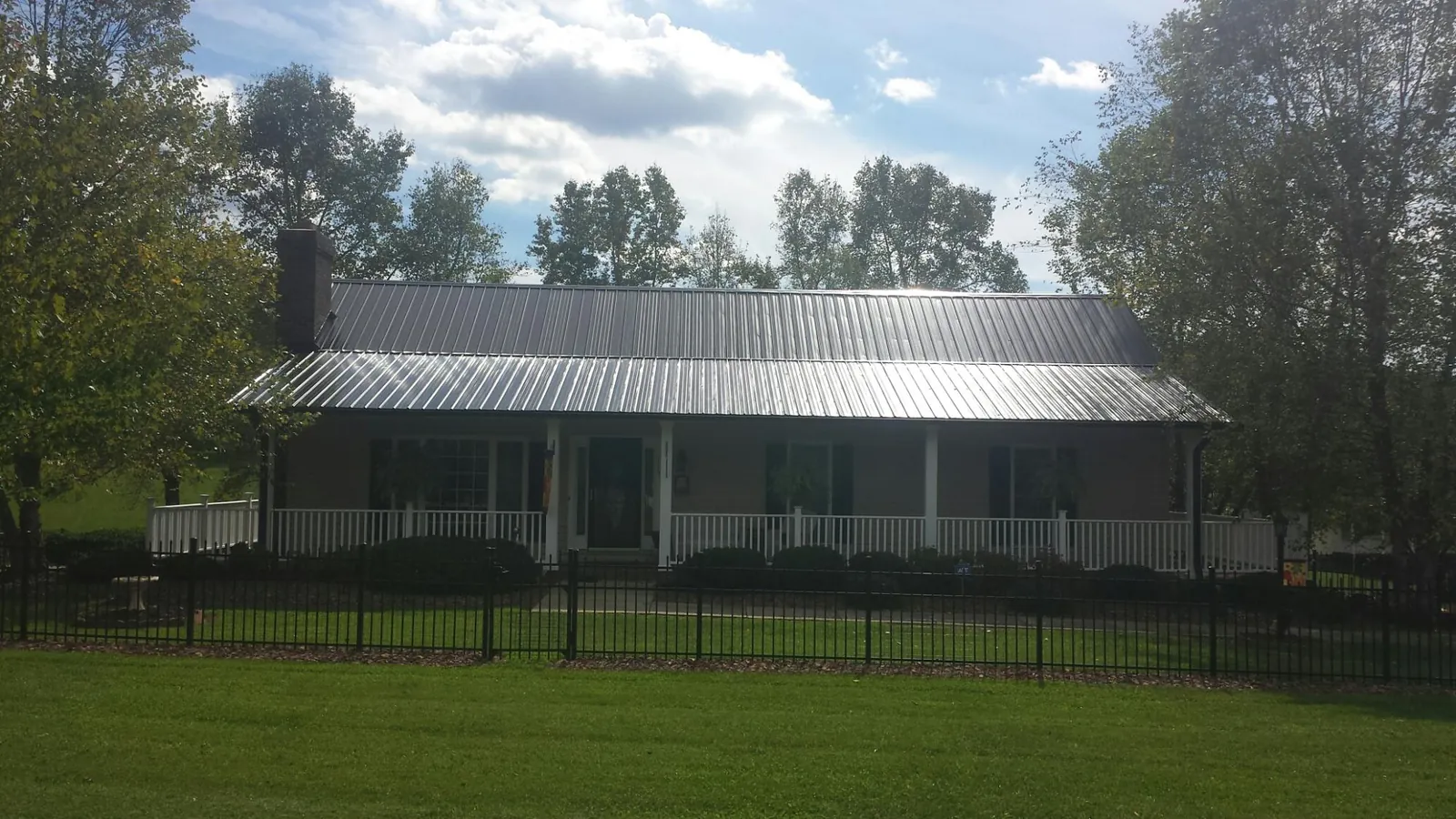 Gray metal roof on a brick ranch with a full width front porch — Gutter Guard Installation work by our crew in Jobstown