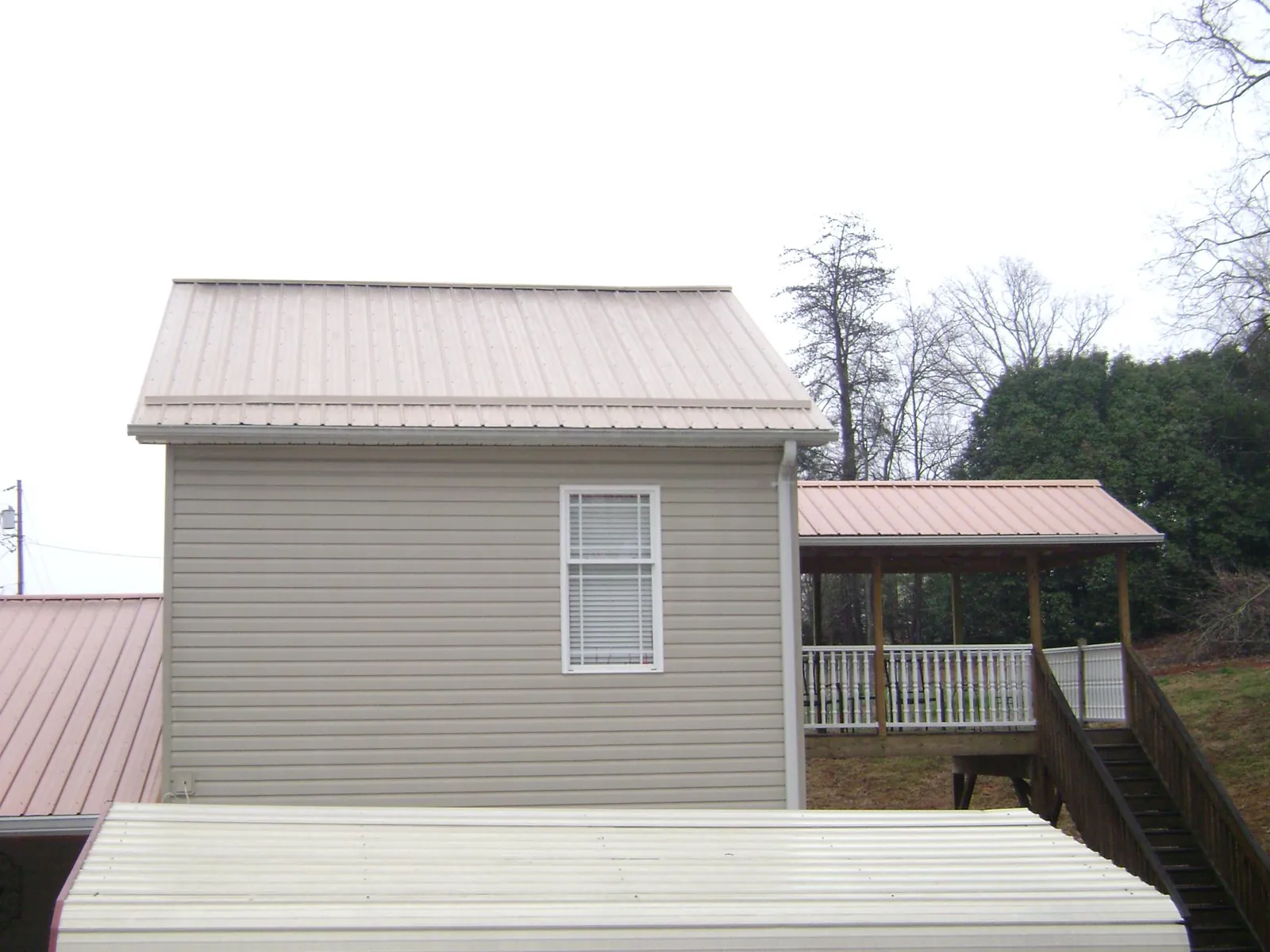 Tan metal roofs on a two story addition and attached porch, from a Roof Replacement job in Jobstown