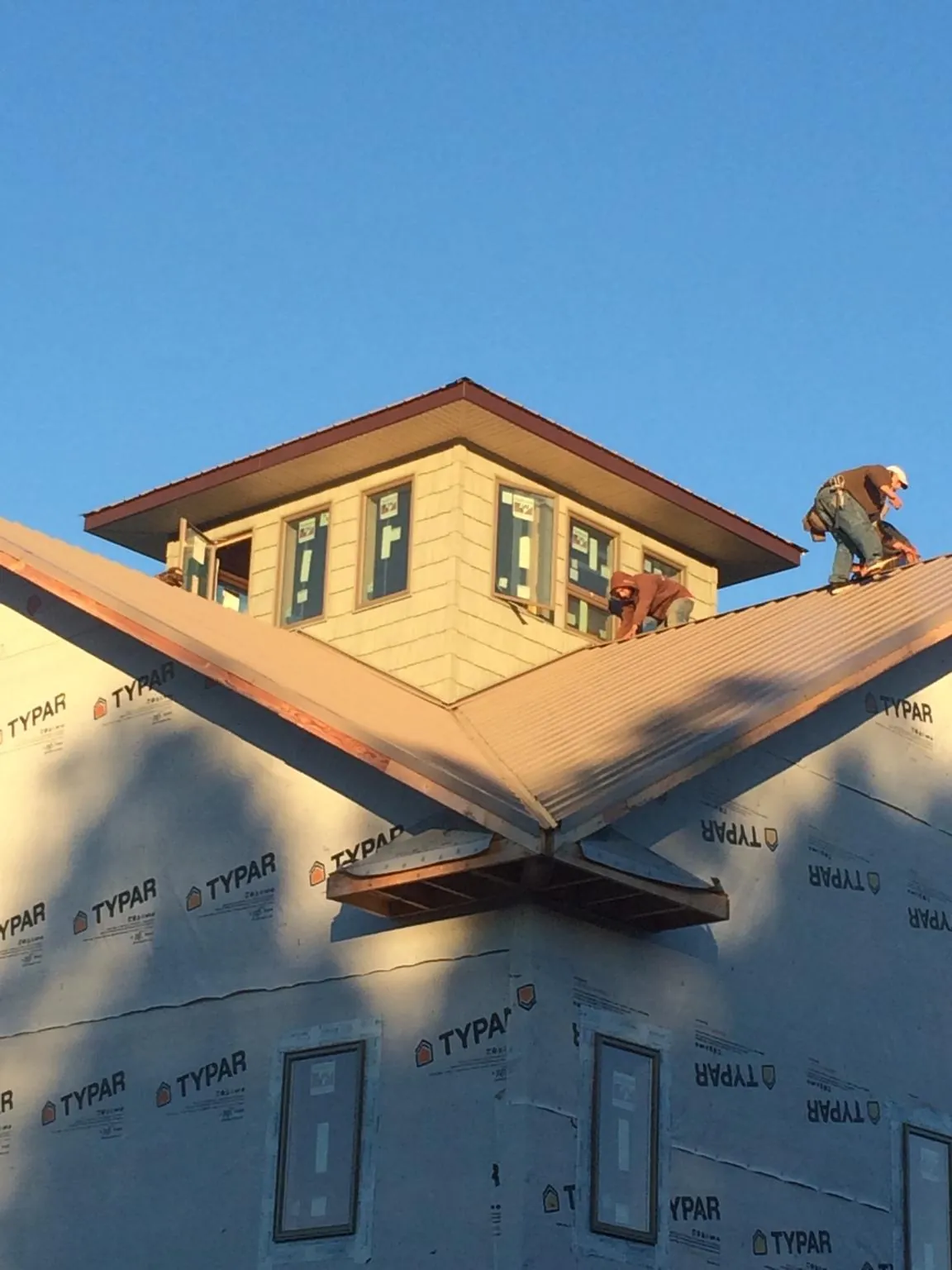 Roofers working around a rooftop cupola on a new metal roof at sunset — Roof Waterproofing in Jobstown by Roofing Brothers